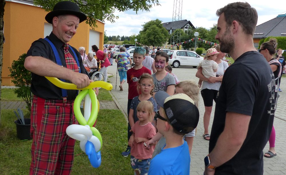 Ein Clown formt für ein Kind ein Tier aus Ballons. Anlass war die Einweihung Spielplatz